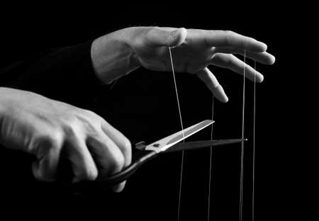 Man cutting strings on hands with scissors. Abuse, violence, slavery cessation. Overcoming addiction...