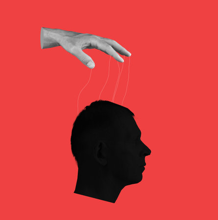 Control over human mind. Hand with strings and head on red background. Manipulation of person consciousness, thoughts, opinion. High quality photoの写真素材