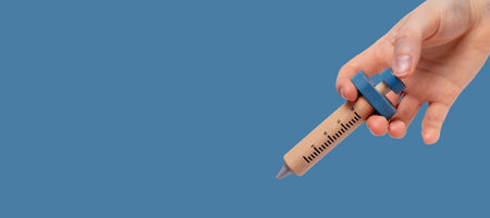 Wood kids syringe toy in female hand close up, injection and vaccination. Banner with copy space.の写真素材