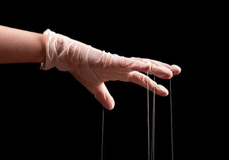 Hand in glove manipulates. Manipulation, authority concept. High quality photoの写真素材