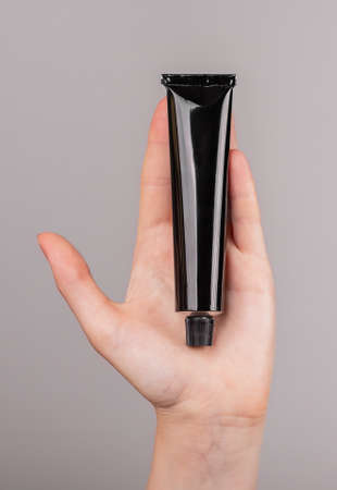 Hand holding cream tube mockup. Skin care, cosmetics concept. Black template. High quality photo