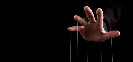Hand closeup pulling strings, manipulating, controlling. Authority concept. Banner with copy space for text.の写真素材