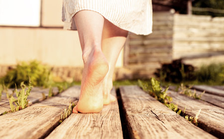 Girls feet walking on wood planks in nature. Women barefoot legs going outdoors. high quality photoの写真素材