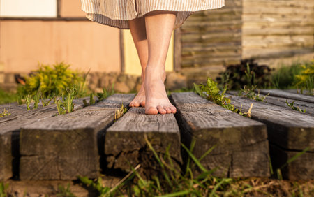 Girls feet walking on wood planks in nature. Women barefoot legs going outdoors. high quality photoの写真素材