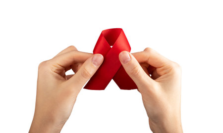 Red satin ribbon in hand isolated on white background. HIV and AIDS awareness day symbol. High quality photoの写真素材
