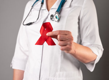 Red satin loop ribbon in doctors hand, symbol of HIV and AIDS day. 1 December support and care. High quality photoの写真素材