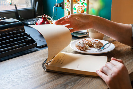 Hand with paper notebook, organizer at cafe desk, wood table, looking through tasks, plans. high quality photoの写真素材