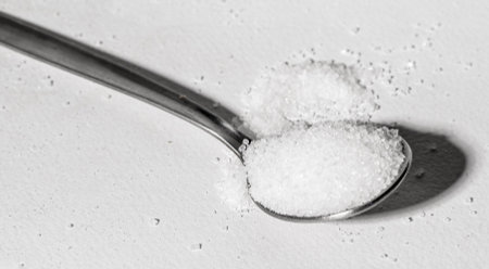 Full teaspoon of sweet white sugar, beet sweetener. Metal tea spoon of granulated crystals of sweet sucrose. high quality photoの写真素材