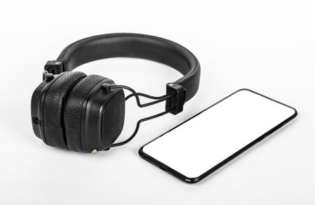 Mobile phone mockup and black wireless headphones. Smartphone display mock up for audio application, audiobook app ad. High quality photoの写真素材