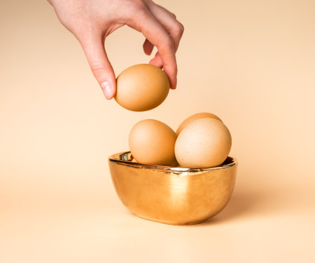 Easter eggs dyed, painted in gold beige natural color for spring religious holiday. Hand taking egg. high quality photoの写真素材