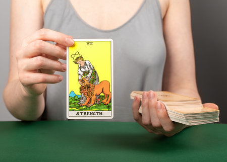 Lodz Poland April 15 2023 Strength arcana, hand holding showing tarot card during divination.