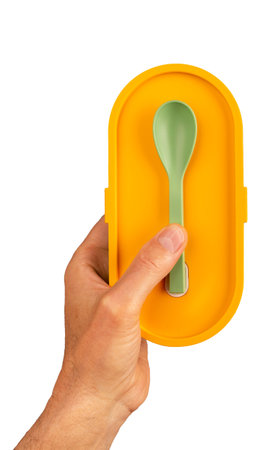 Hands holding lunch box and small spoon. Lunchbox, food container isolated on white.の写真素材