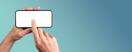 Hand holding smartphone, clicking on blank screen mock-up, tapping on mobile phone display. Banner...