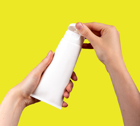 Hands holding cream tube mock-up, blank beauty product mockup isolated on white, opening lid, cap.の写真素材