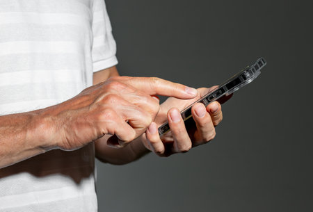 Hand holding mobile phone, finger tapping on screen.の写真素材