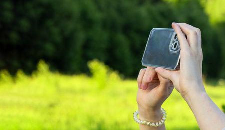 Berlin, Germany July 15 2023 Hands holding phone, taking photo, recording video in nature. Banner.のeditorial素材