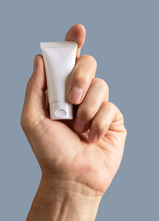 Male hand holding cream tube, cosmetic product mockup, blank package for beauty liquid.の写真素材