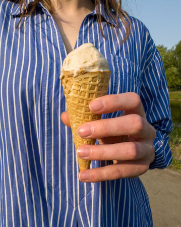 Ice-cream in waffle cone in hand clos-up shot, summer holiday.