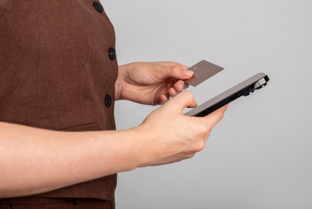 Hand holding mobile phone and bank card, paying online through internetのeditorial素材