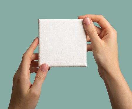 Hand holding blank white canvas mockup of square shapeの写真素材