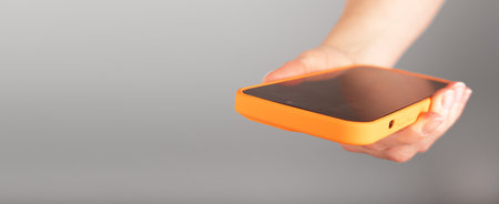 Hand holding mobile phone, smartphone, cellphone closeup. Banner background, copy space for text.