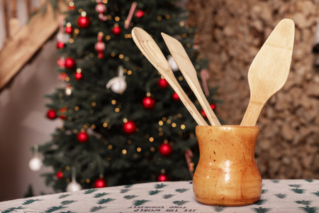 Kitchen with Christmas table, holiday tree xmas cooking. Winter rustic wood decor gift. Background festive new set home utensils above. Dining tablecloth cloth spoon red topの写真素材