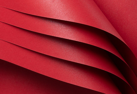Scarlet red paper with a vivid gradient and glowing, shiny surface. The premium material features layered folds and geometric lines, creating a luxurious and glamorous backdrop.の写真素材