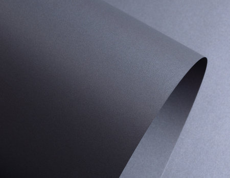 Designer paper background with a dark gray, graphite texture featuring wavy, curved shapes and a subtle gradient. The crinkled, twisted surface adds depth, while fine layers andの写真素材