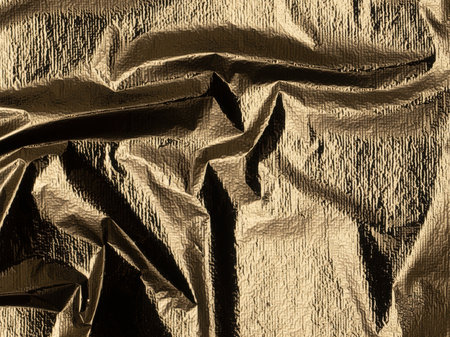 Golden foil with a shiny, polished sheen. Elegant, reflective fabric with a crumpled texture and beautiful, warm tones. Stylish vertical drapery, showcasing a metallic alloy design with a smooth,の写真素材
