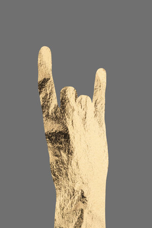 Rock gesture with hand showing golden metallic horns, symbolizing energy, rebellion, and enthusiasm. Expression of freedom and creativity in music culture, celebrating heavy metal and concert vibes.の写真素材