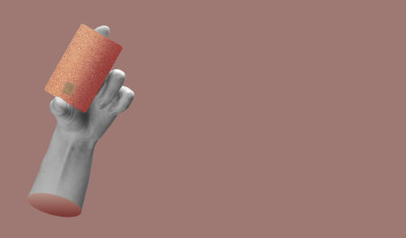 Hand holding a credit card with a gold chip, symbolizing secure digital payment and finance transactions. Modern, minimal design with a sleek, red background. Ideal for shopping, banking, and economicの写真素材