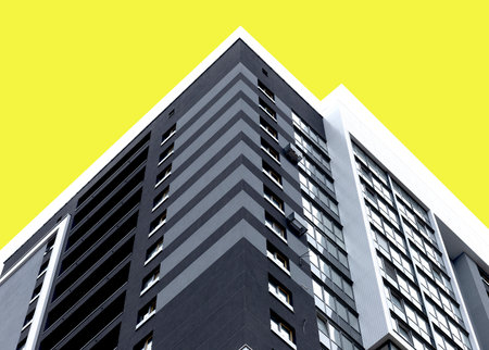 Building corner with modern high rise architecture and yellow facade. Geometric vertical structure symbolizing stylish urban housing, real estate investment and contemporary design. Isolated on whiteの写真素材
