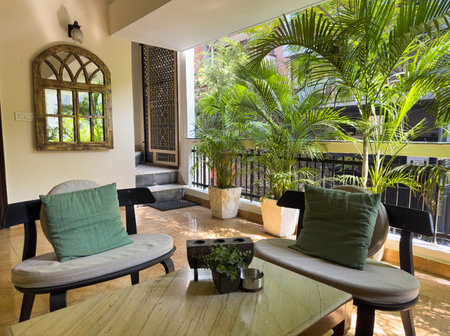 Cozy balcony with tropical plants, green foliage, and comfortable seating. Stylish veranda with chair, table, and cushions. Peaceful, bright design with natural decor, perfect for relaxation and rest.の写真素材