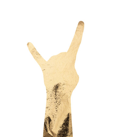 Hand gesture showing rock horns symbol in gold foil texture. Bold silhouette with shiny metallic surface, cool attitude, cultural expression and modern glam style. Isolated on white background.の写真素材