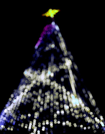 A beautifully decorated Christmas tree with glowing lights and sparkling bokeh effects. The unfocused, shimmering glow creates a festive and stylish backdrop for the holiday season. Isolated on blue,の写真素材