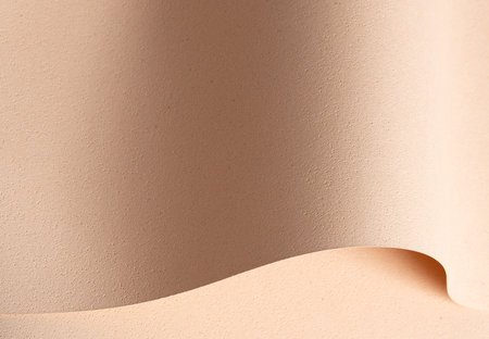 Elegant designer paper in beige and cream tones with rough grained texture and pierced surface. Curved wavy shape adds a tactile, minimalistic touch in modern premium style. Close up background.の写真素材