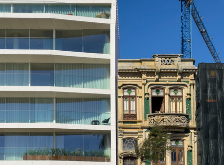 Contrast of architecture in Porto, Portugal, showing an ornate historic building with decorative facade next to a sleek modern apartment with glass balconies. Old versus new styles side by side in theの写真素材