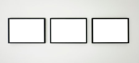 Three horizontal black picture frames hanging on a white wall, clean mockup for artwork, photography, posters, or graphic design presentation in a modern minimalist interior.の写真素材
