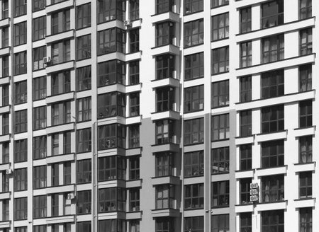 Close up of modern high rise residential building facade. Multiple glass windows and balconies...