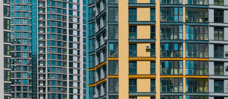 Close up of modern high rise residential tower. Multiple glass windows and balconies create geometric facade pattern. Urban architecture, housing, property and real estate development.の写真素材