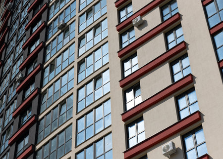 Close up of tall modern high rise apartment tower. Multiple glass windows create geometric facade in urban setting. City architecture, housing, property and real estate investment.の写真素材