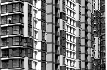 Close up of modern high rise residential building facade. Multiple glass windows and balconies form geometric pattern. Urban architecture, housing, property and real estate investment.の写真素材
