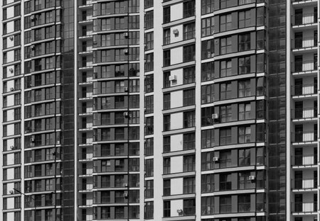 Closeup of tall urban high rise tower. Multiple glass windows and balconies form geometric facade...