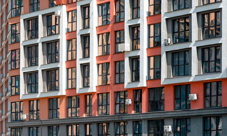 Close up of modern urban tower. Tall multi storey residential building with glass windows and geometric facade pattern. City architecture, housing, home and real estate investment.の写真素材