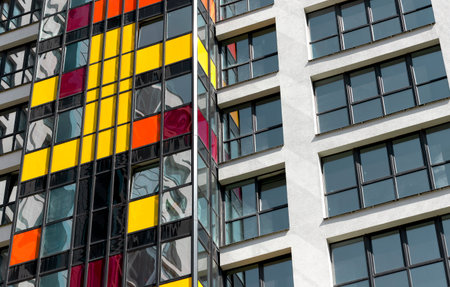 Close up of modern high rise residential tower. Multiple glass windows and balconies form colorful...
