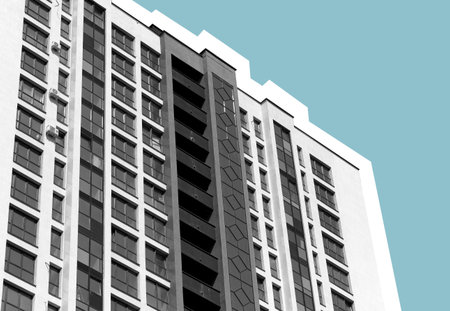 Contemporary multistory building with glass facade and balconies in sunny metropolitan neighborhood....