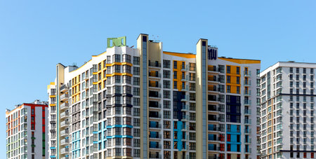 Colorful tall building with balconies and windows under sunny blue sky in metropolitan city. Modern...