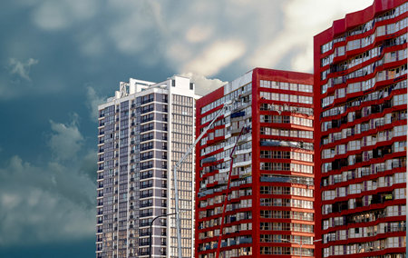 Developing urban building in downtown district. Tall residential apartment structure with modern facade and windows under cloudy sky. City architecture, housing, property and real estate investment.の写真素材