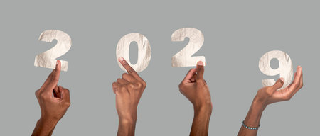 2029 new year concept of silver celebration. African American hands raised holding metallic number collage, shiny foil texture, festive christmas and business typography design isolated on whiteの写真素材