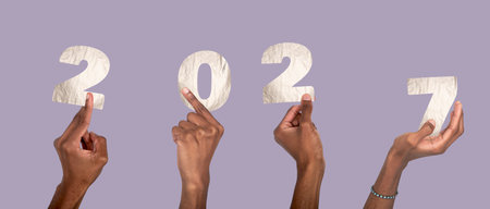 2027 new year celebration concept. Hand with raised fingers holding silver metallic number collage, black skin wrist, festive office party mood, christmas and business typography design isolated onの写真素材